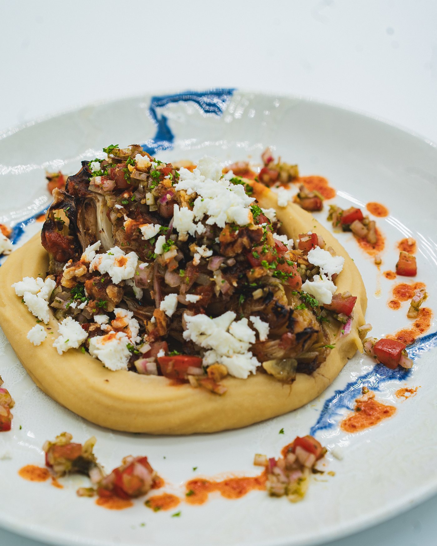 Grilled hispi cabbage on white bean and harissa purée with feta and gremolata