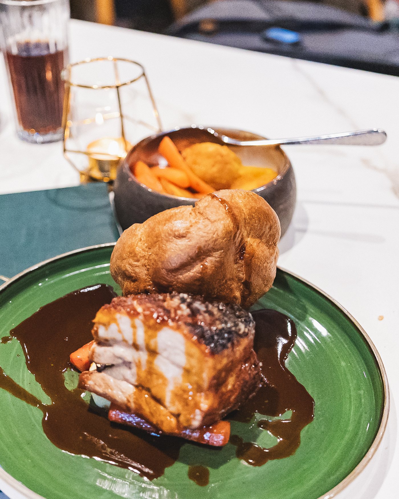Roast pork belly with crackling and a Yorkshire pudding on a green plate