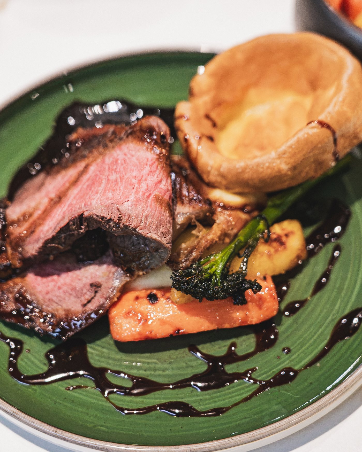 Close view of roast sirloin, Yorkshire pudding, carrot and tender stem broccoli
