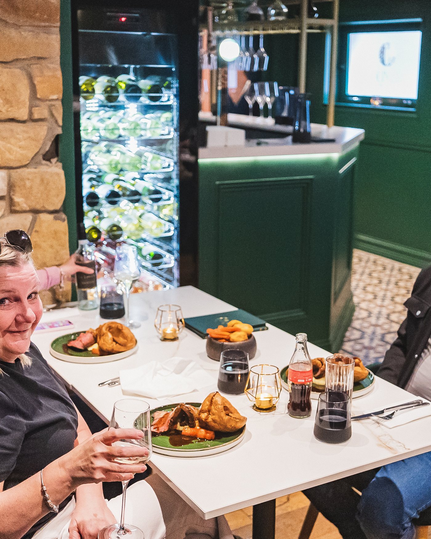 Guests at a table in the dining room raising a glass over their Sunday roasts
