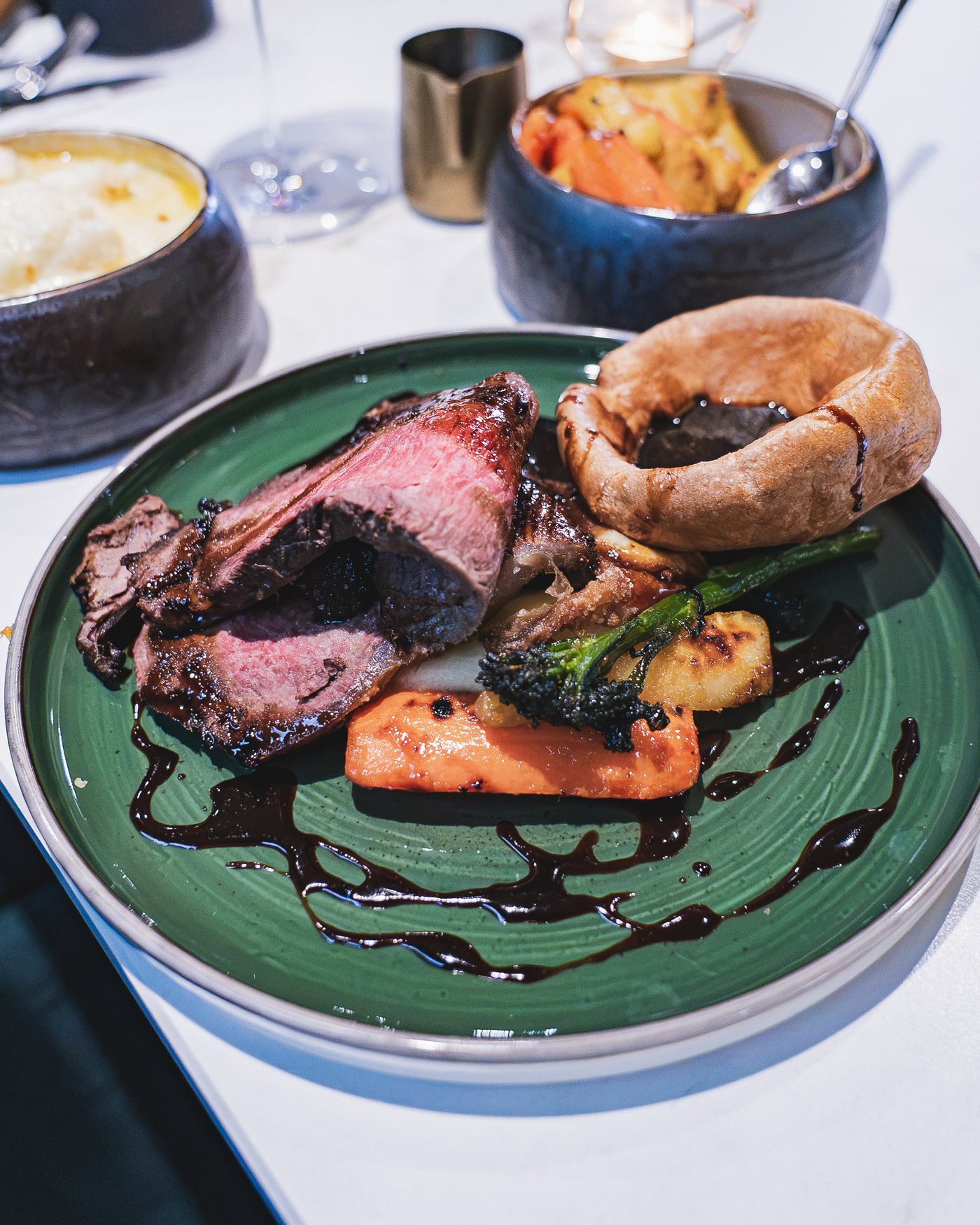 A Sunday roast of sirloin with a Yorkshire pudding and red wine jus, with sides on the table
