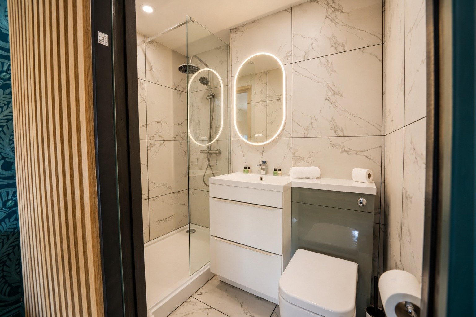 A second en-suite bathroom with marble tiling, a walk-in shower and an illuminated mirror