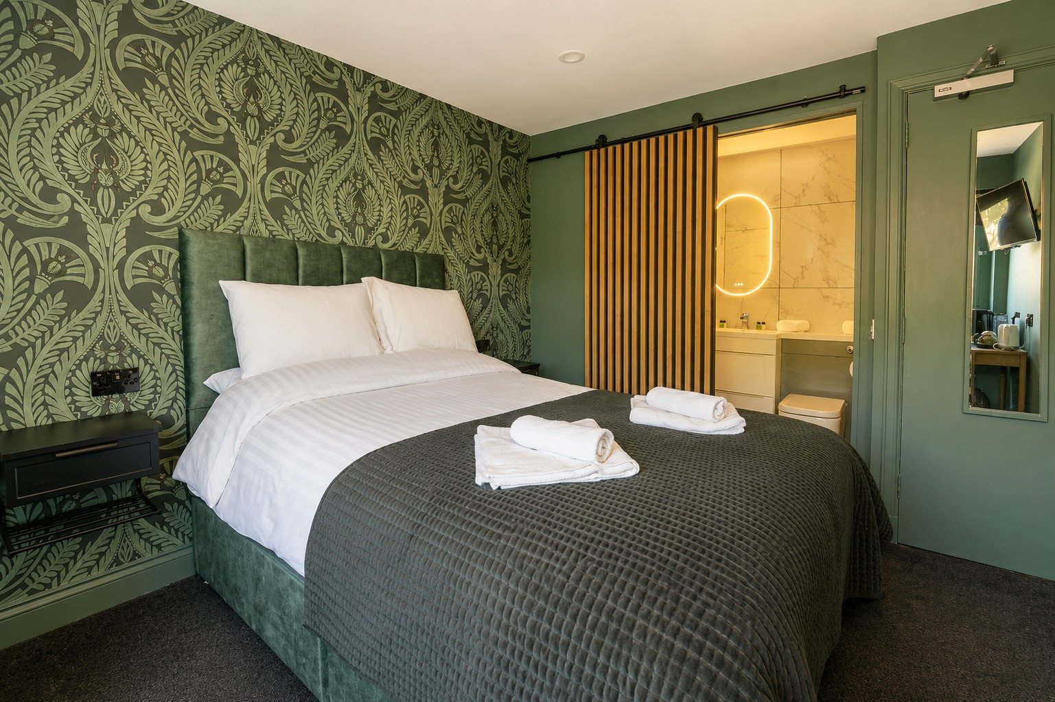 The green damask room with its own en-suite bathroom visible through a sliding oak door