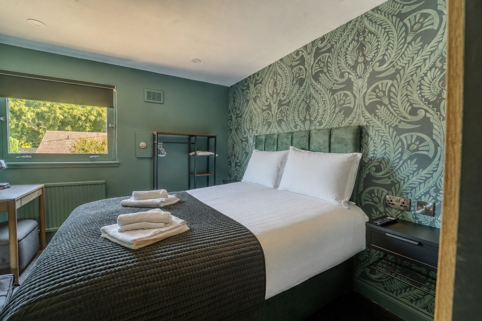 The green damask room seen wide, with desk, window and wardrobe rail